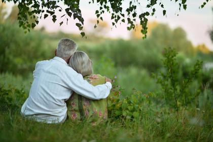 Older couple sitting under a tree in grassy field