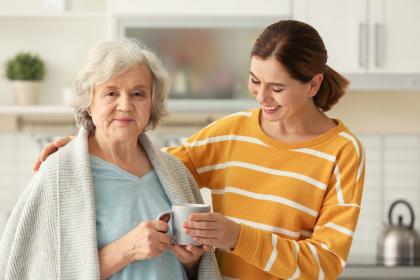 Daughter and daughter caregiver having coffee in the kitchen.