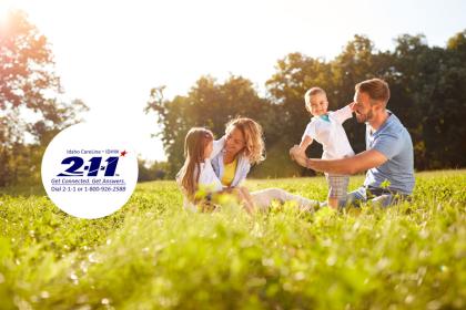 Banner with logo and young family in the background sitting in a grassy field.