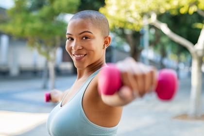 Woman cancer survivor holding dumbbells in a park