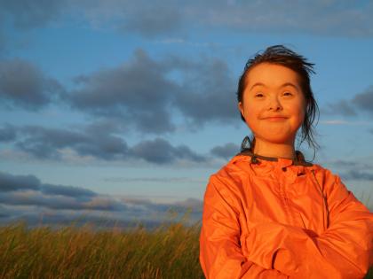 Happy girl with Downs Syndrome standing in a field