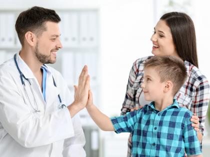 Young boy high-fives doctor with mother