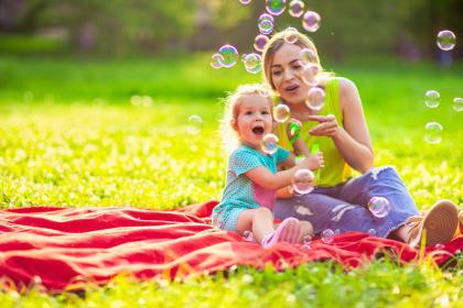 Mother and daughter playing with bubbles in grass