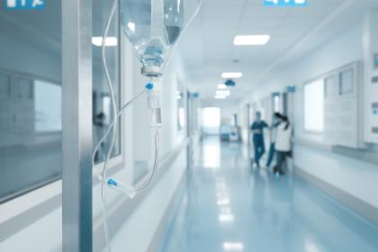Hospital hallway with intravenous drip in foreground and doctors in the background
