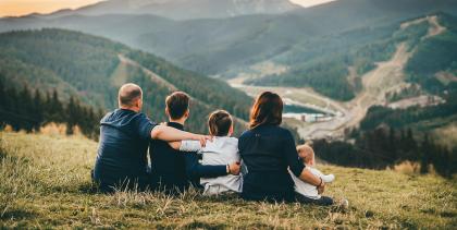 Parents and three children sitting on hillside looking into a river valley